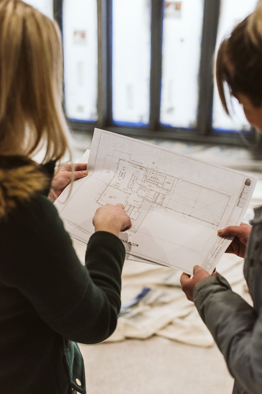 two people are looking at a blueprint of a house .