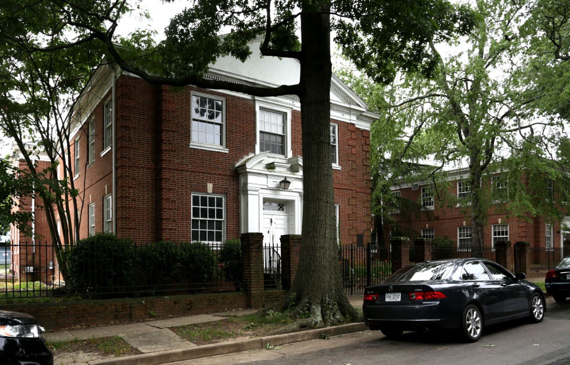 A black car is parked in front of a brick building.
