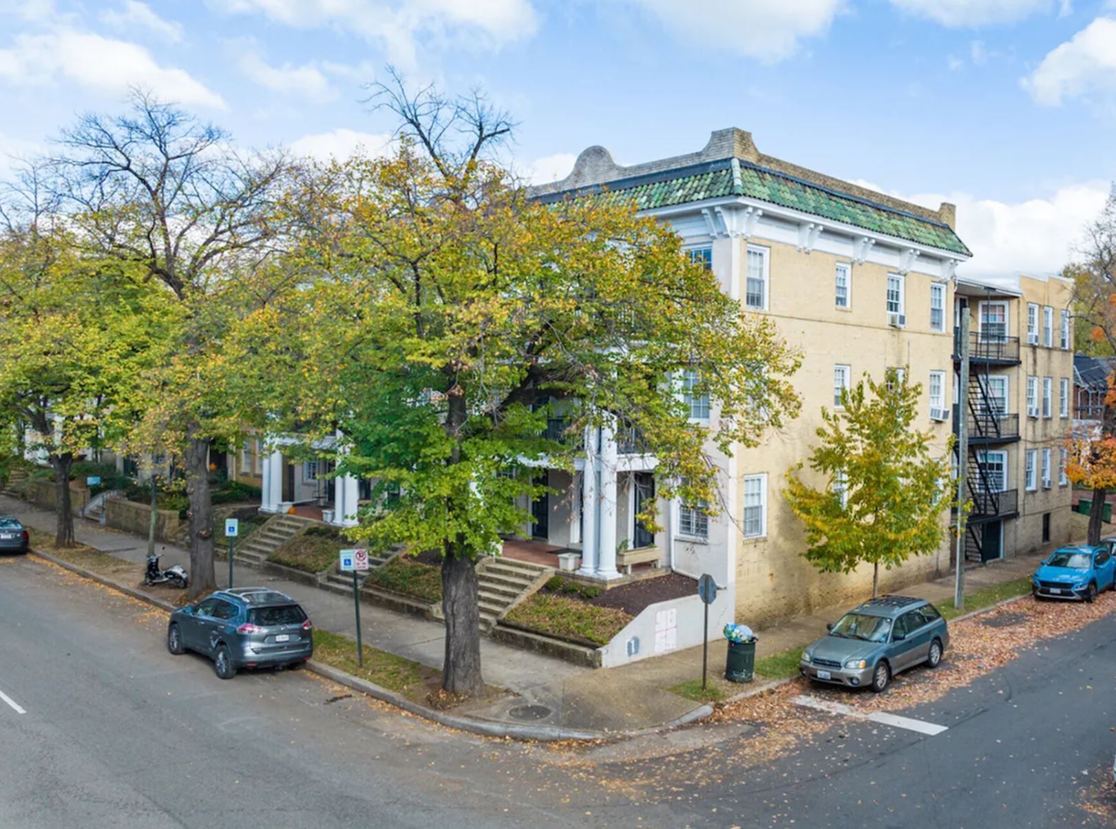 An aerial view of a large apartment building with cars parked in front of it.