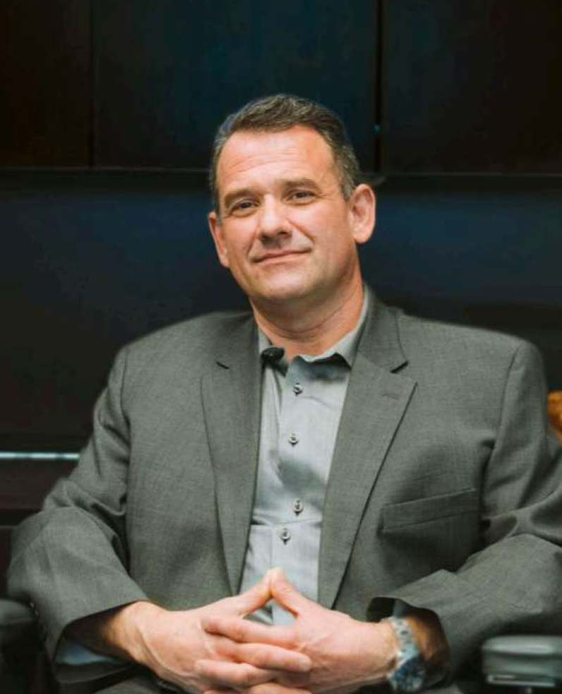 A man is sitting on a couch talking to two older people.