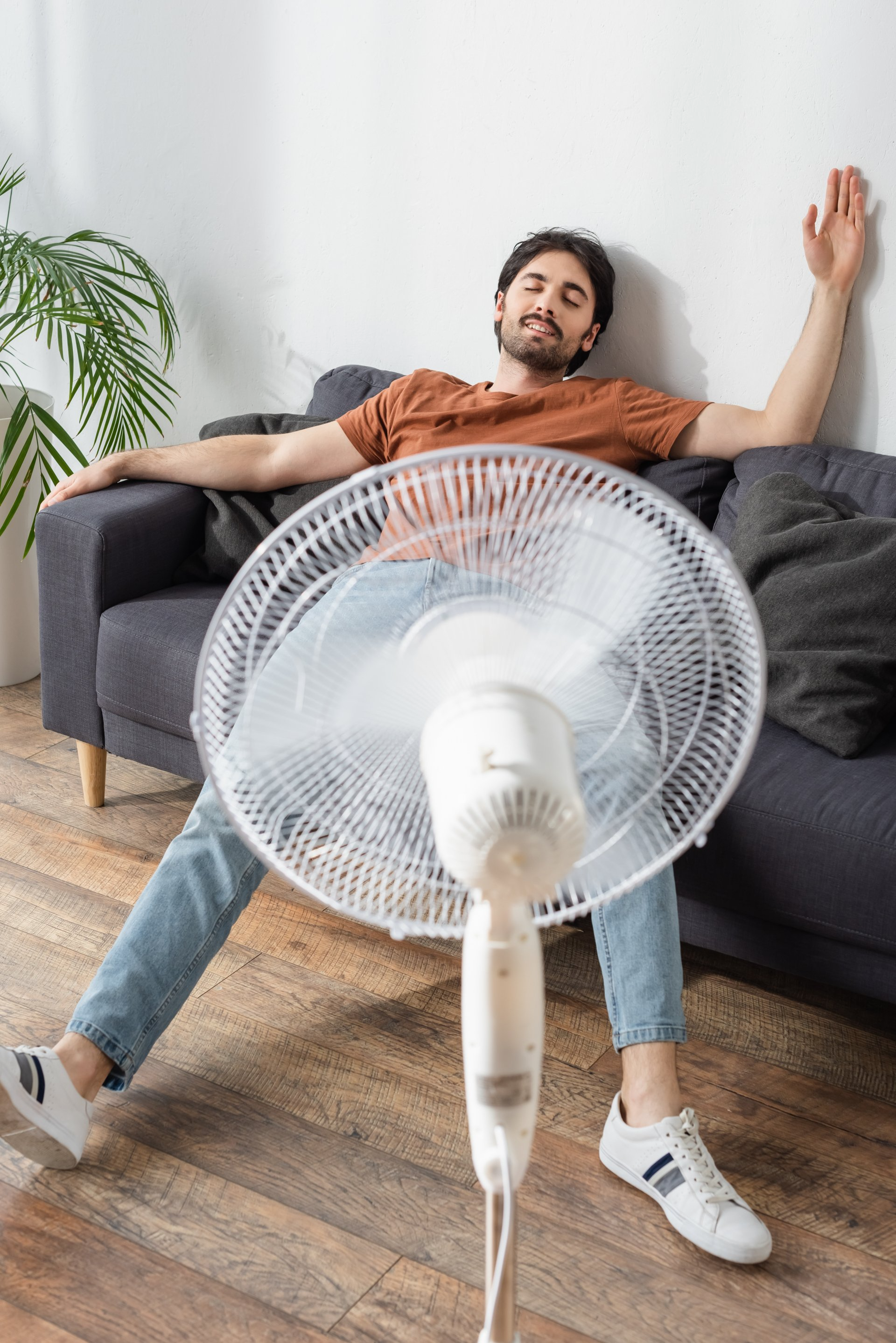 man sitting on couch in front of fan