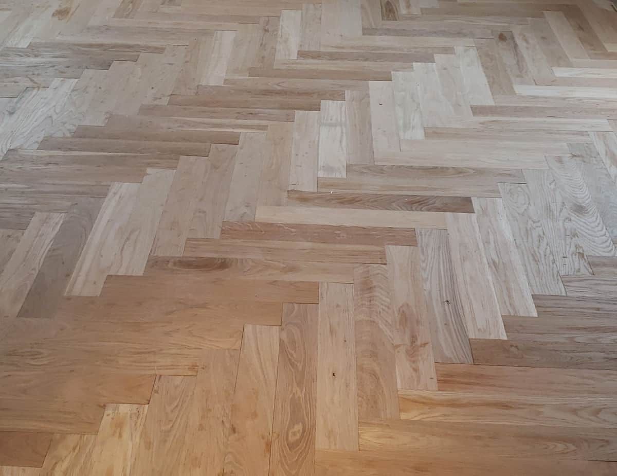 Herringbone pattern hardwood floor in light brown.