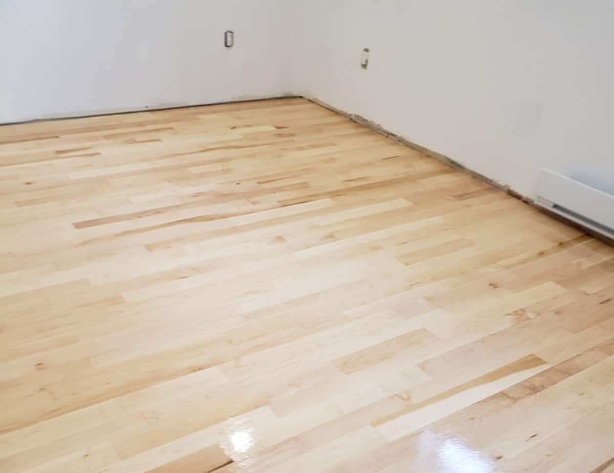 Hardwood flooring in an empty room with white walls and baseboards.