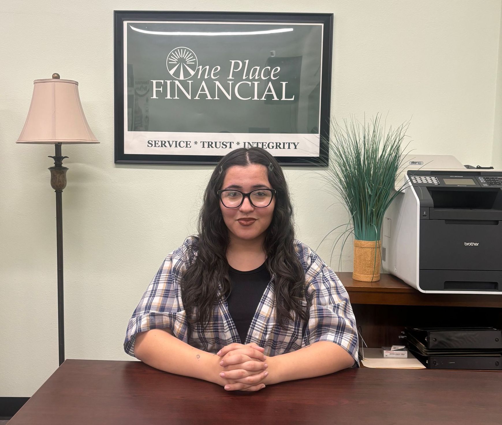 A woman is smiling in front of a one place financial sign