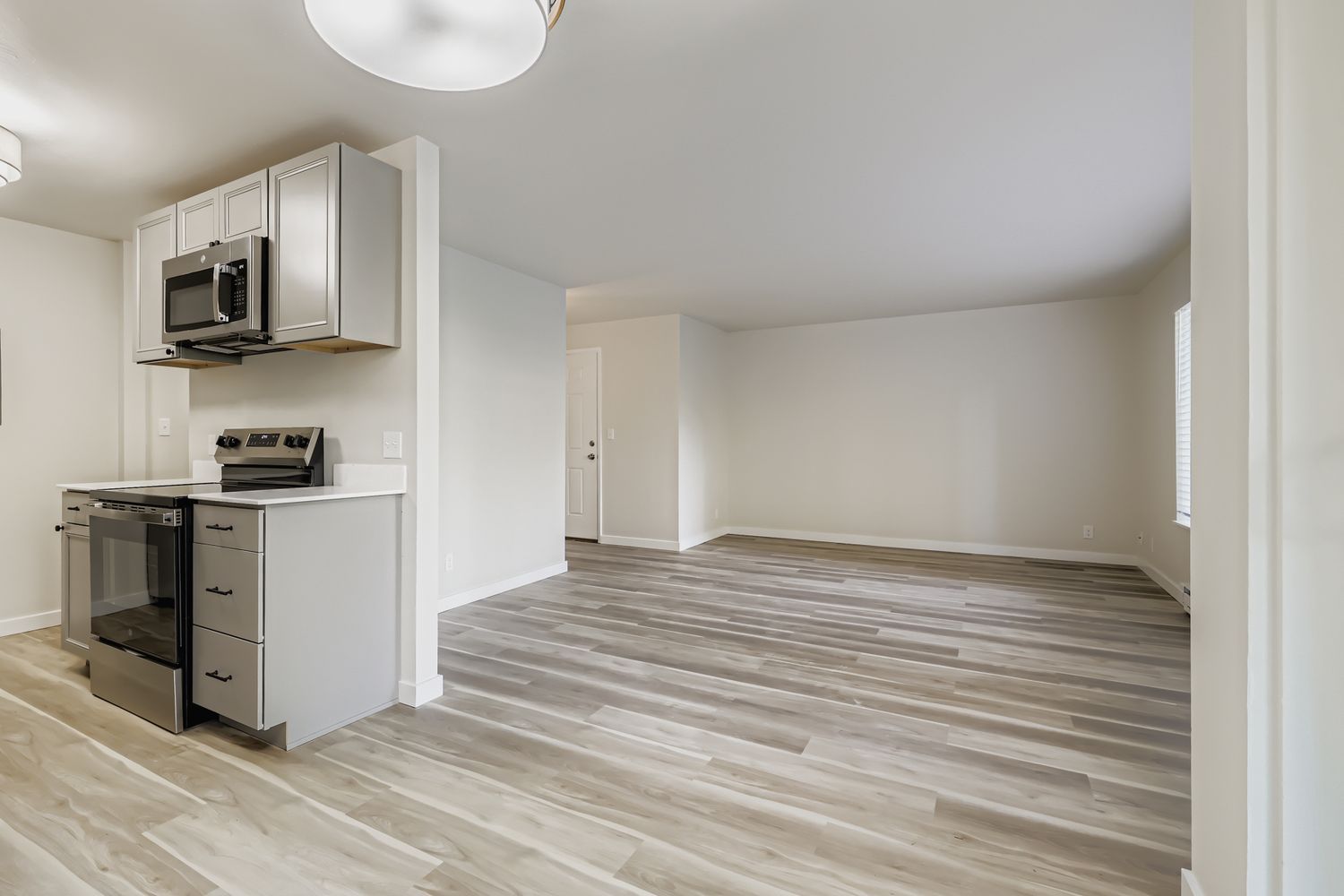 Photo of a large living room in the background with the kitchen and dining area in the foreground and middleground