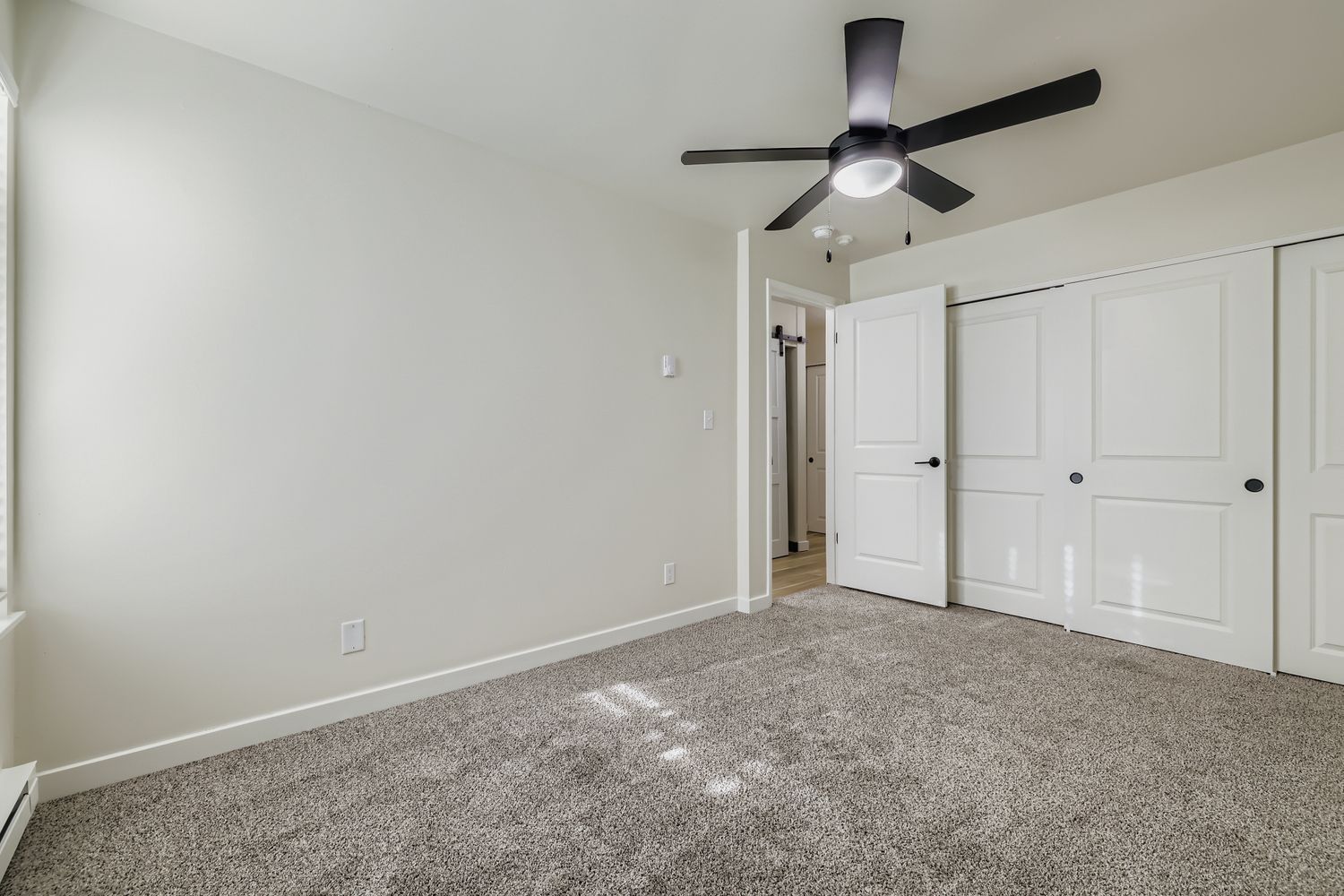 Photo of a large, carpeted bedroom with a ceiling fan and plenty of closet space