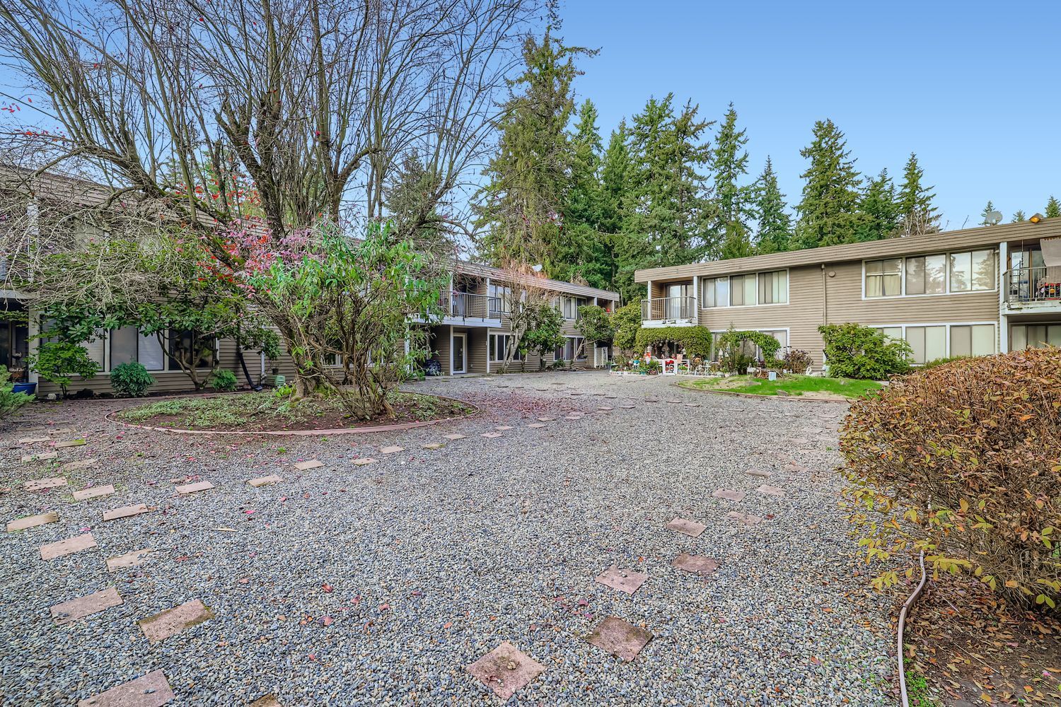 Photo of a path that appears to be paved with pebbles and small rocks, approaching a pair of two-story buildings