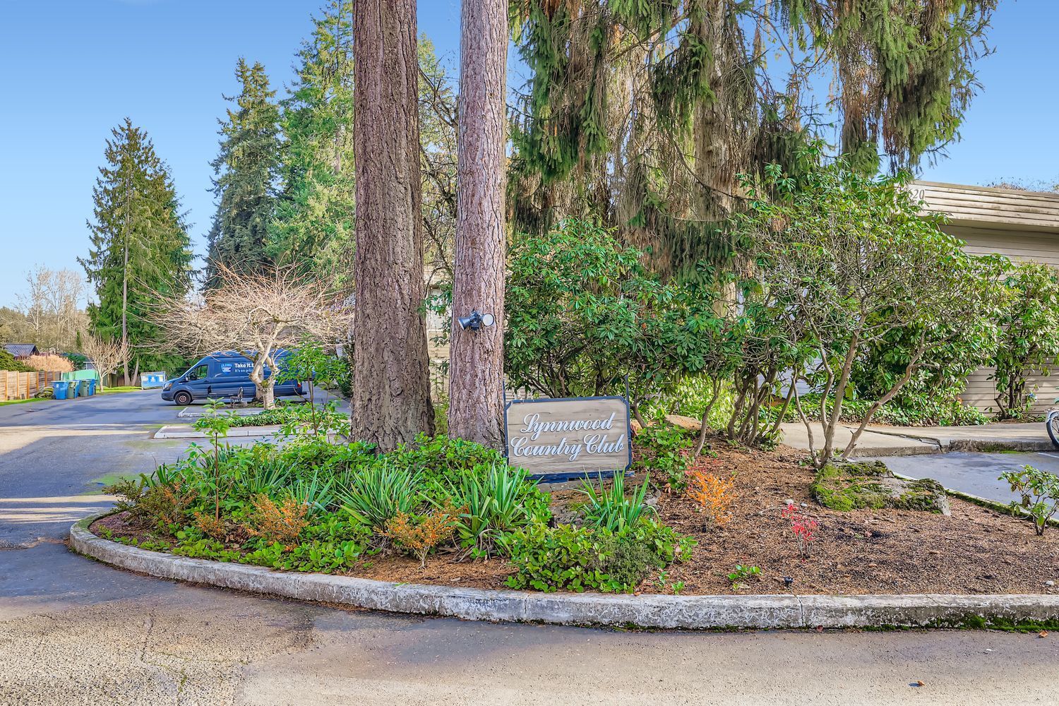 Photo of the entrance area to the community, showing lush grounds and a parking lot