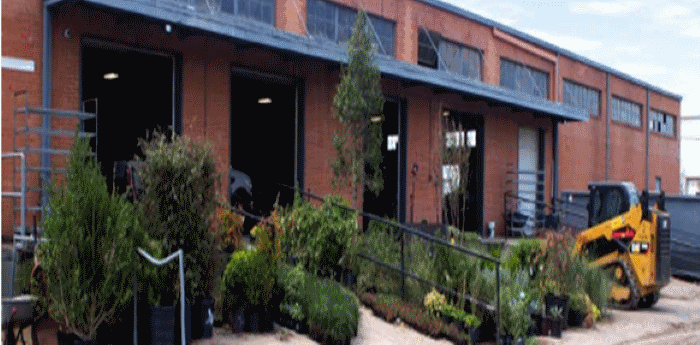 A large brick building with a lot of potted plants in front of it.