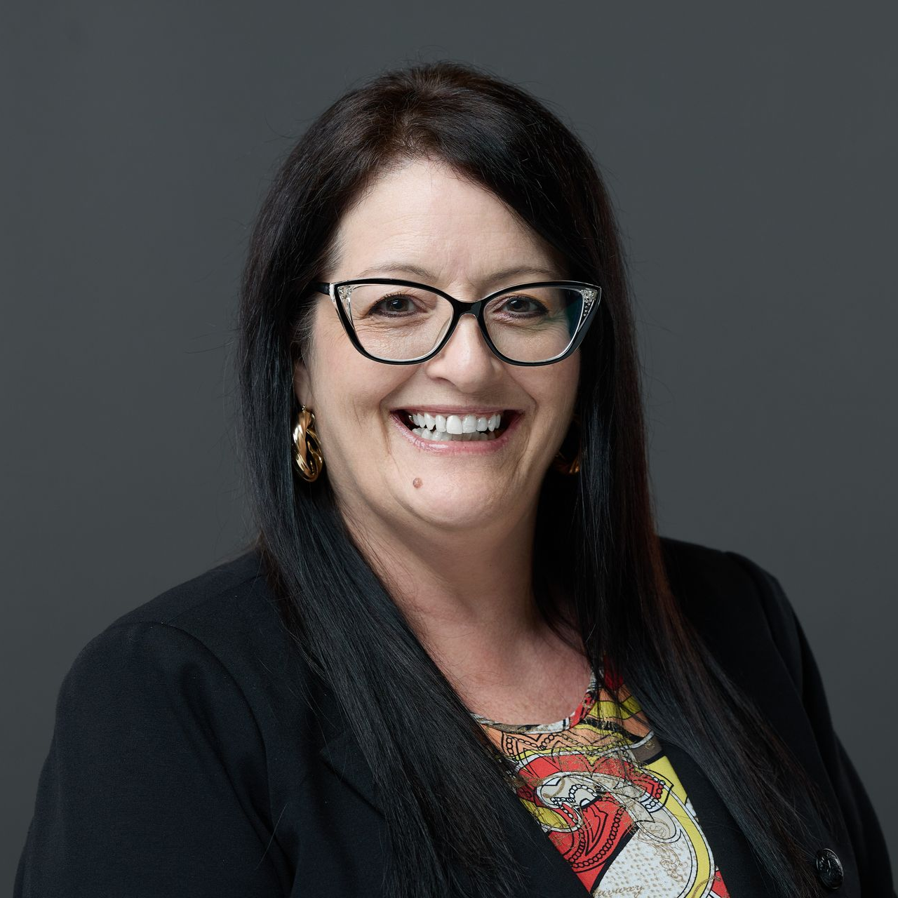 A woman in a suit and white shirt is smiling for the camera.