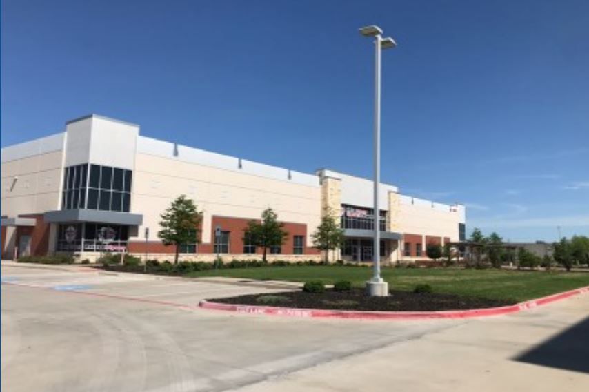 A large building with a lot of windows and a parking lot in front of it