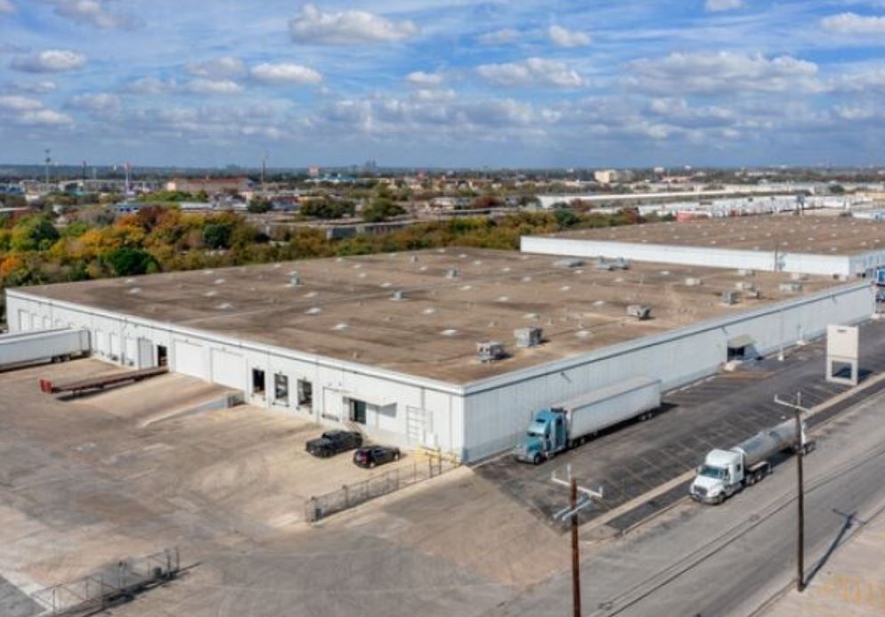 An aerial view of a large warehouse with trucks parked in front of it.