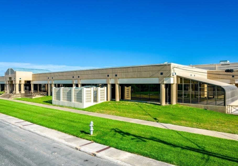 A large building with a lot of windows is sitting on top of a lush green field.