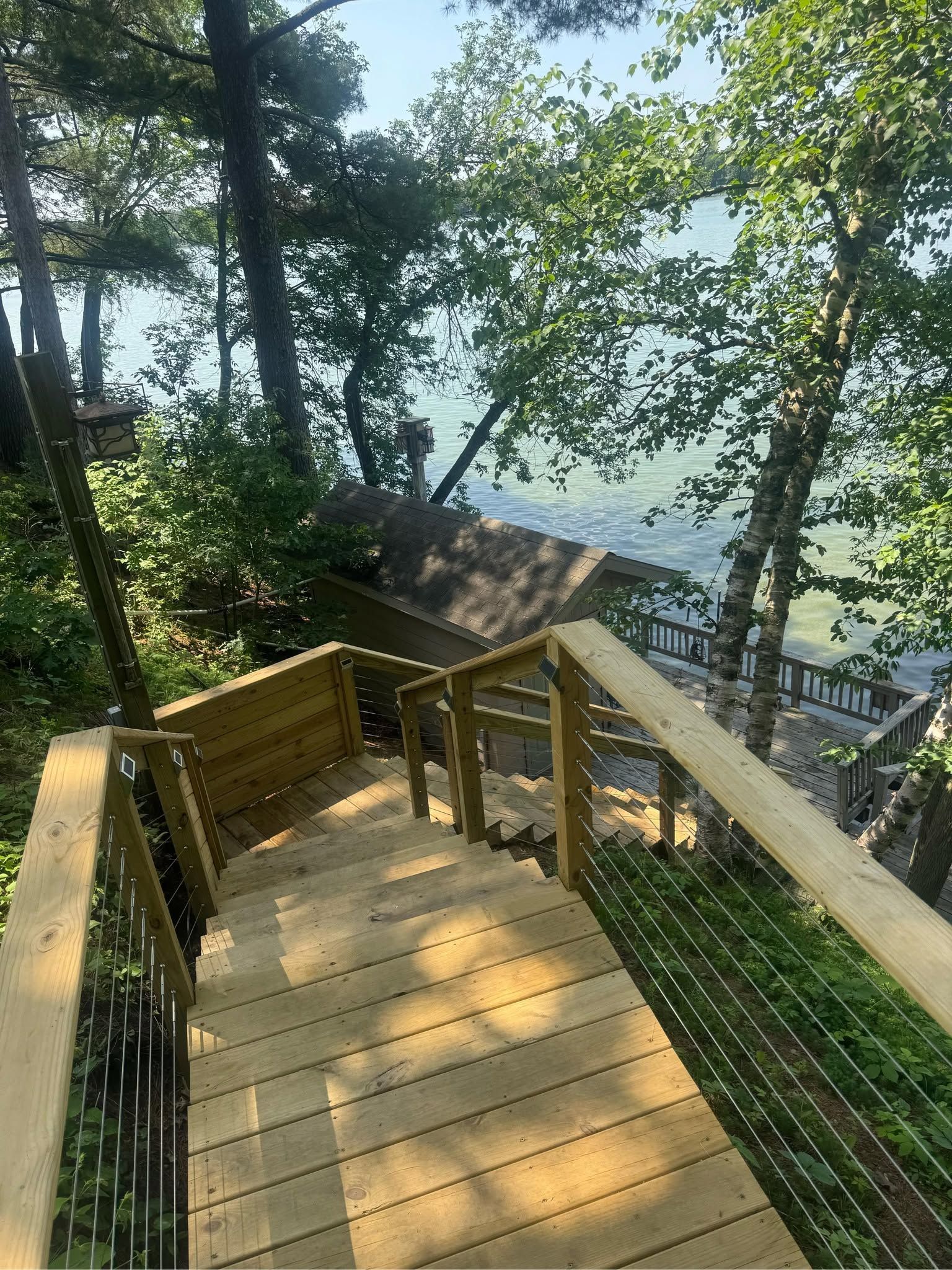 Wooden staircase descending through trees to a lookout over a lake on a sunny day