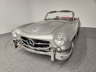A classic silver Mercedes-Benz convertible parked indoors in a well-lit studio setting. A classic silver Mercedes-Benz convertible parked indoors in a well-lit studio setting.
