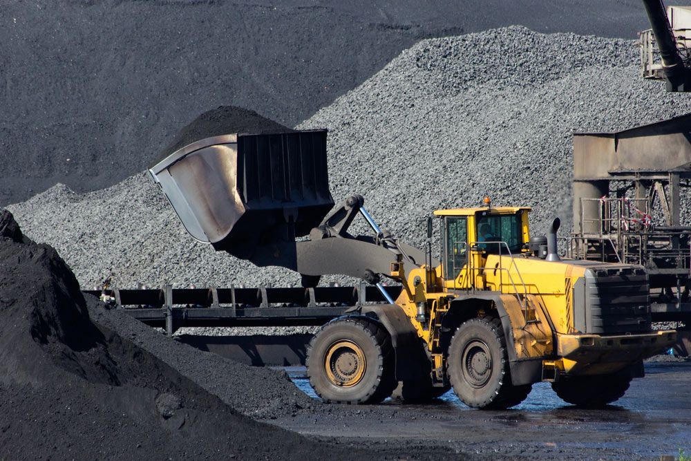 A Yellow Bulldozer Is Loading Coal Into a Truck — Watto's Earthmoving & Machinery Hire in Atherton, QLD
