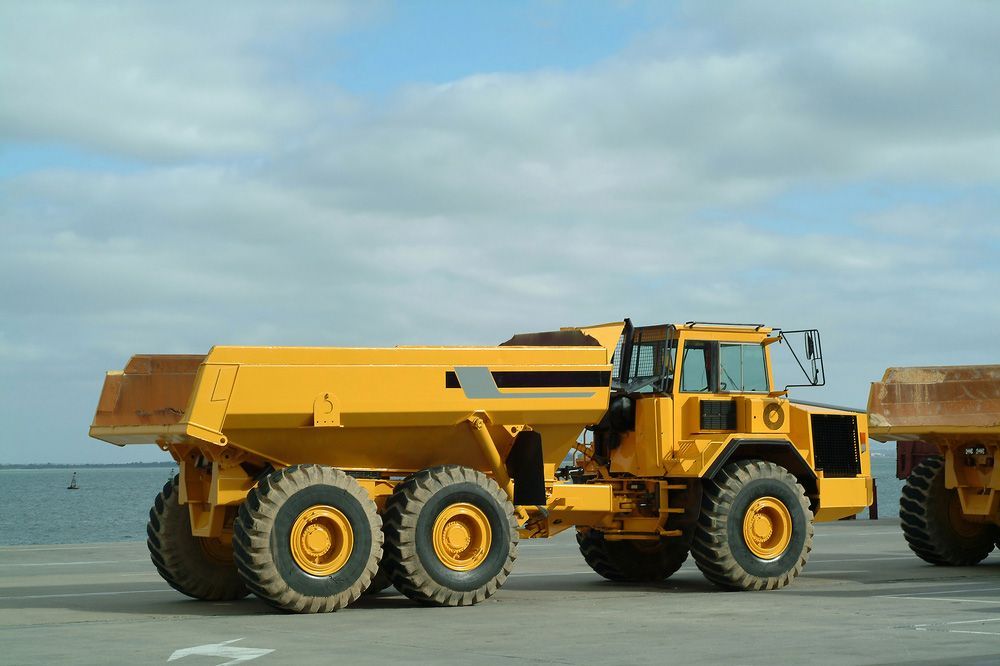 Two Yellow Dump Trucks on A Concrete Surface — Watto's Earthmoving & Machinery Hire in Atherton, QLD