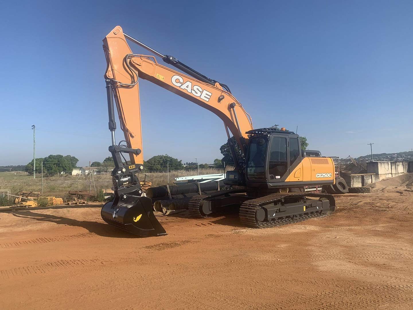 A Case Excavator Is Parked in A Dirt Field — Watto's Earthmoving & Machinery Hire in Atherton, QLD
