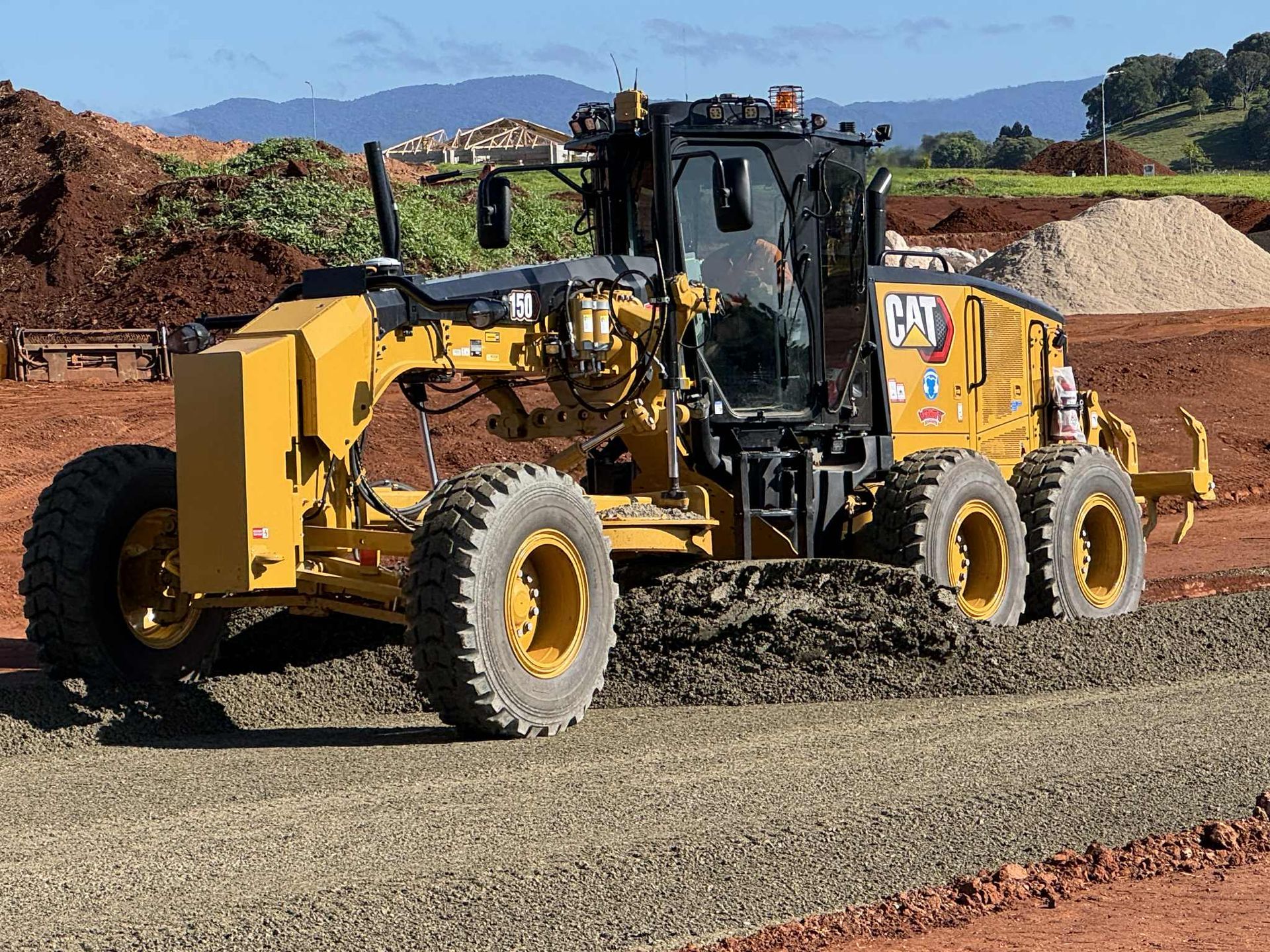 A Yellow Truck Is Spraying Water on Flowers in A Park — Watto's Earthmoving & Machinery Hire in Atherton, QLD