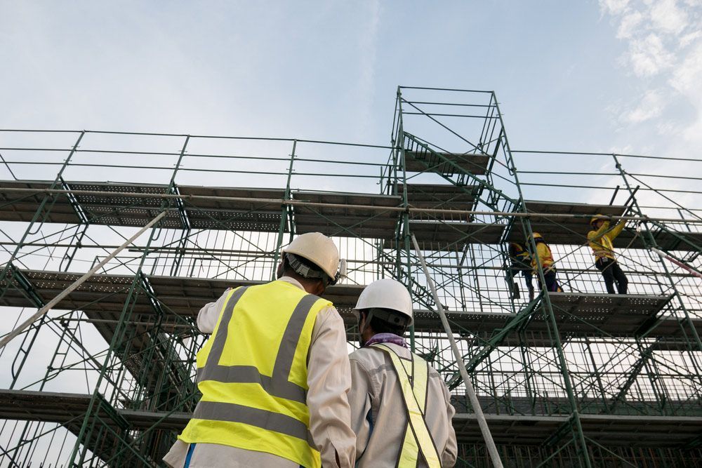 A Couple of Construction Workers Standing on Top of A Scaffolding — Watto's Earthmoving & Machinery Hire in Mareeba, QLD