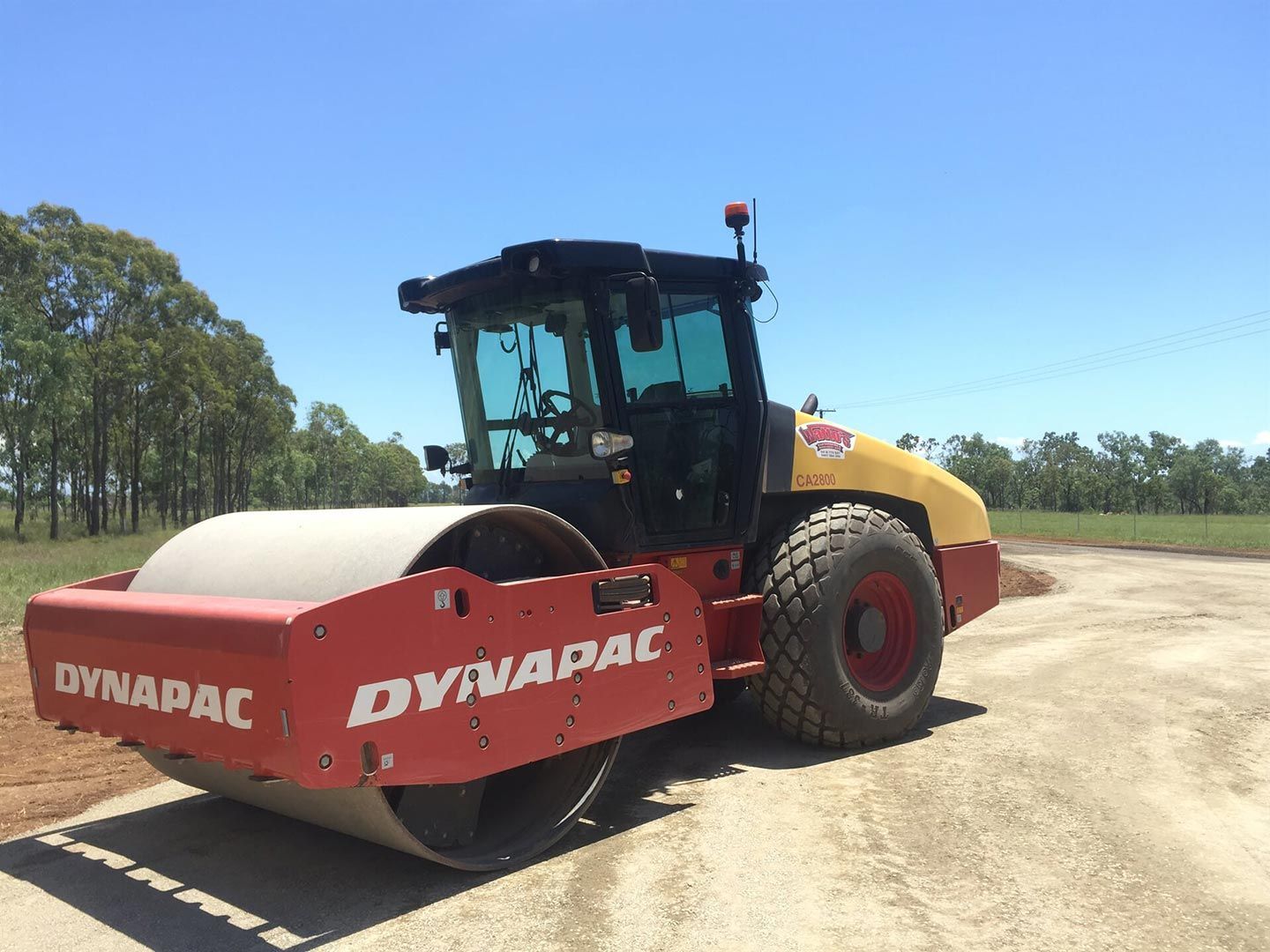 A Red and Yellow Dynapac Road Roller on The Road — Watto's Earthmoving & Machinery Hire in Atherton, QLD