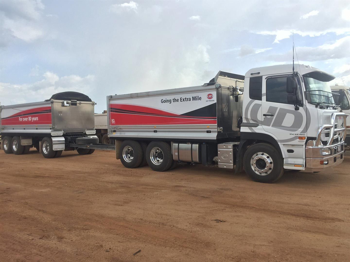 A Dump Truck with A Trailer Attached to It Is Parked in A Dirt Lot — Watto's Earthmoving & Machinery Hire in Atherton, QLD