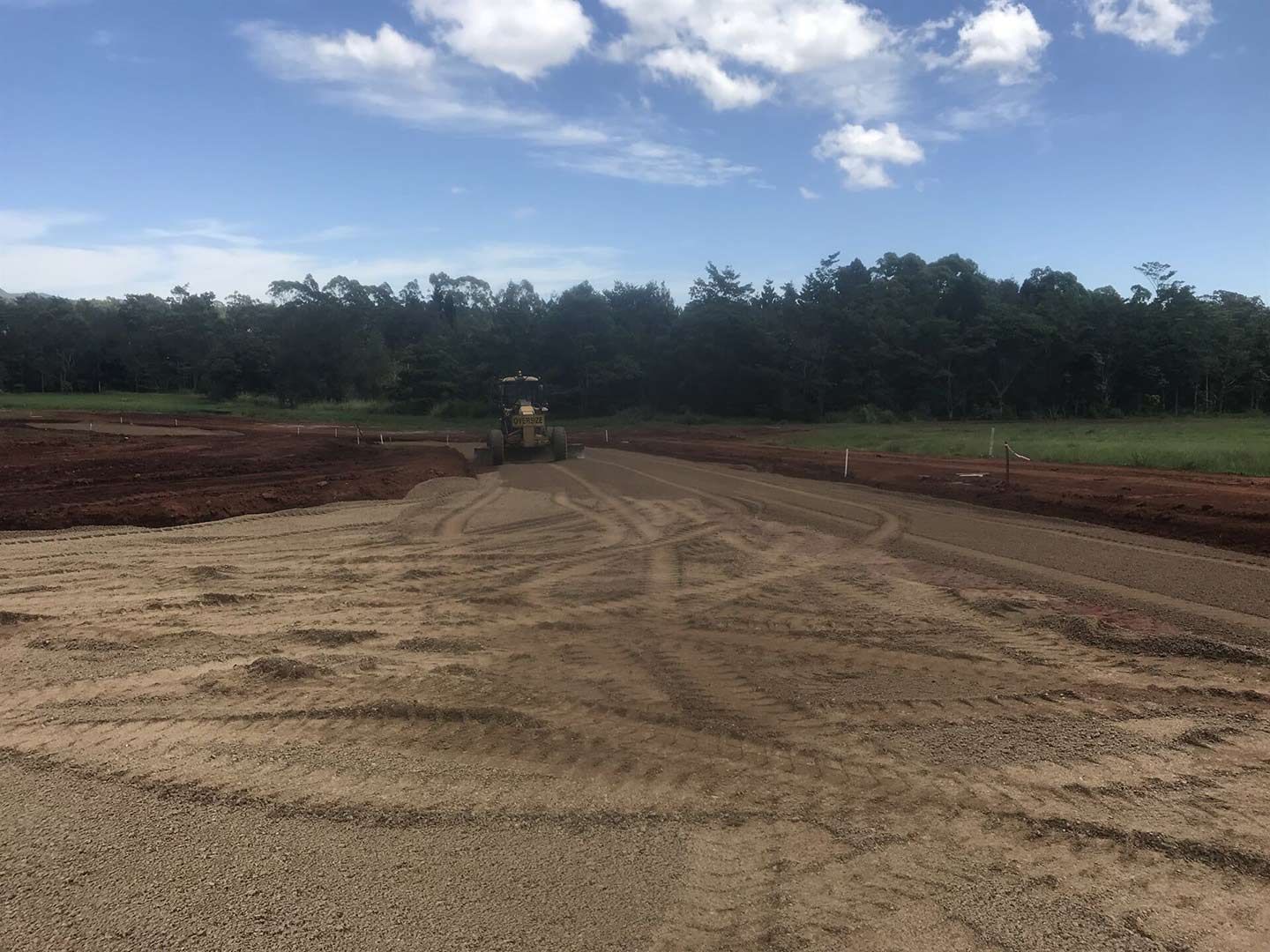 A Tractor Is Driving Down a Dirt Road in A Field — Watto's Earthmoving & Machinery Hire in Atherton, QLD