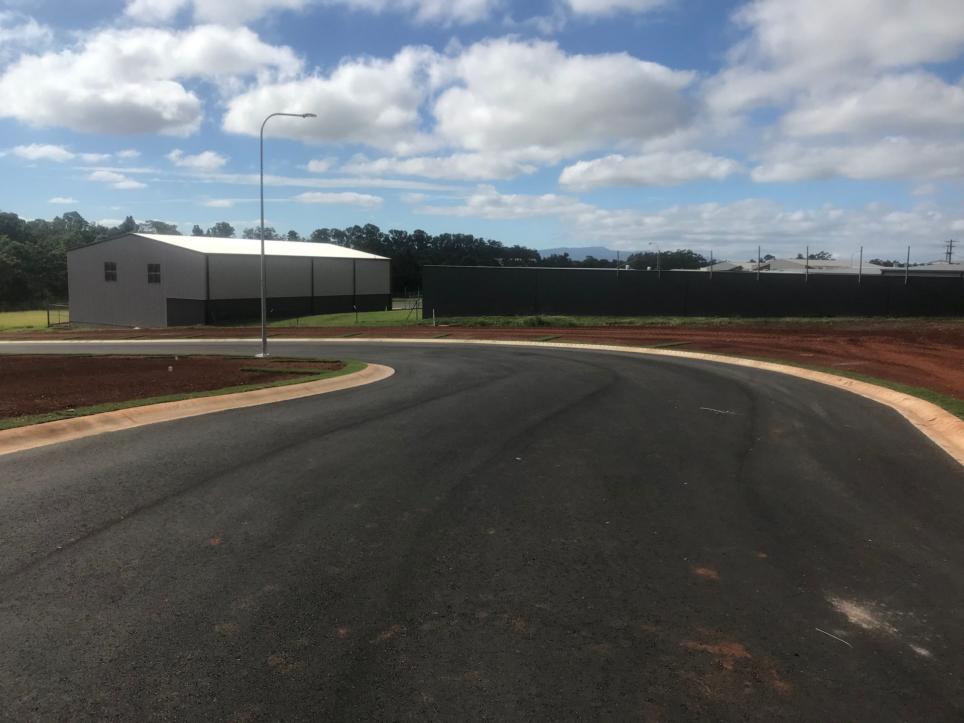 A Dump Truck Is Driving Down a Dirt Road Next to An Excavator — Watto's Earthmoving & Machinery Hire in Atherton, QLD