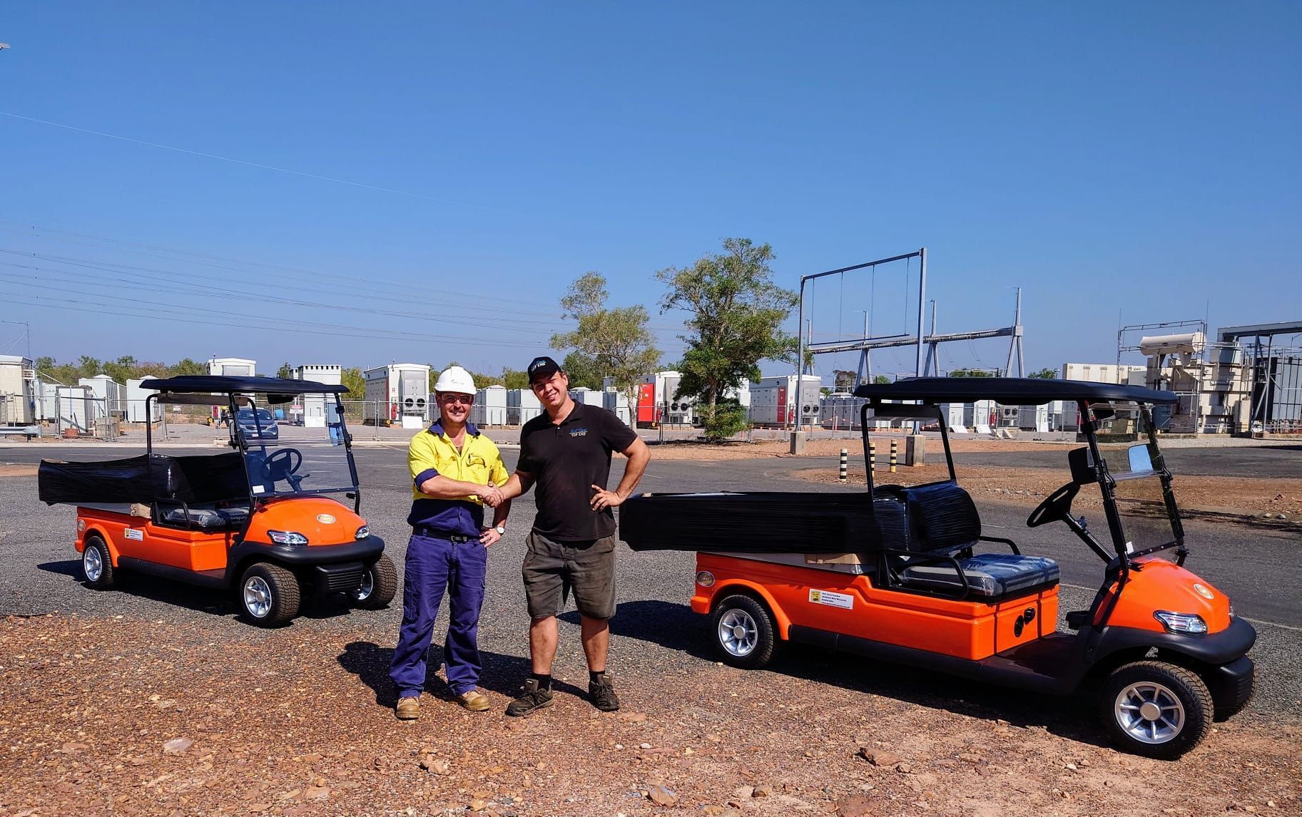 Two Men Are Shaking Hands In Front Of A Golf Cart— Golf Carts Top End in Howard Springs, NT