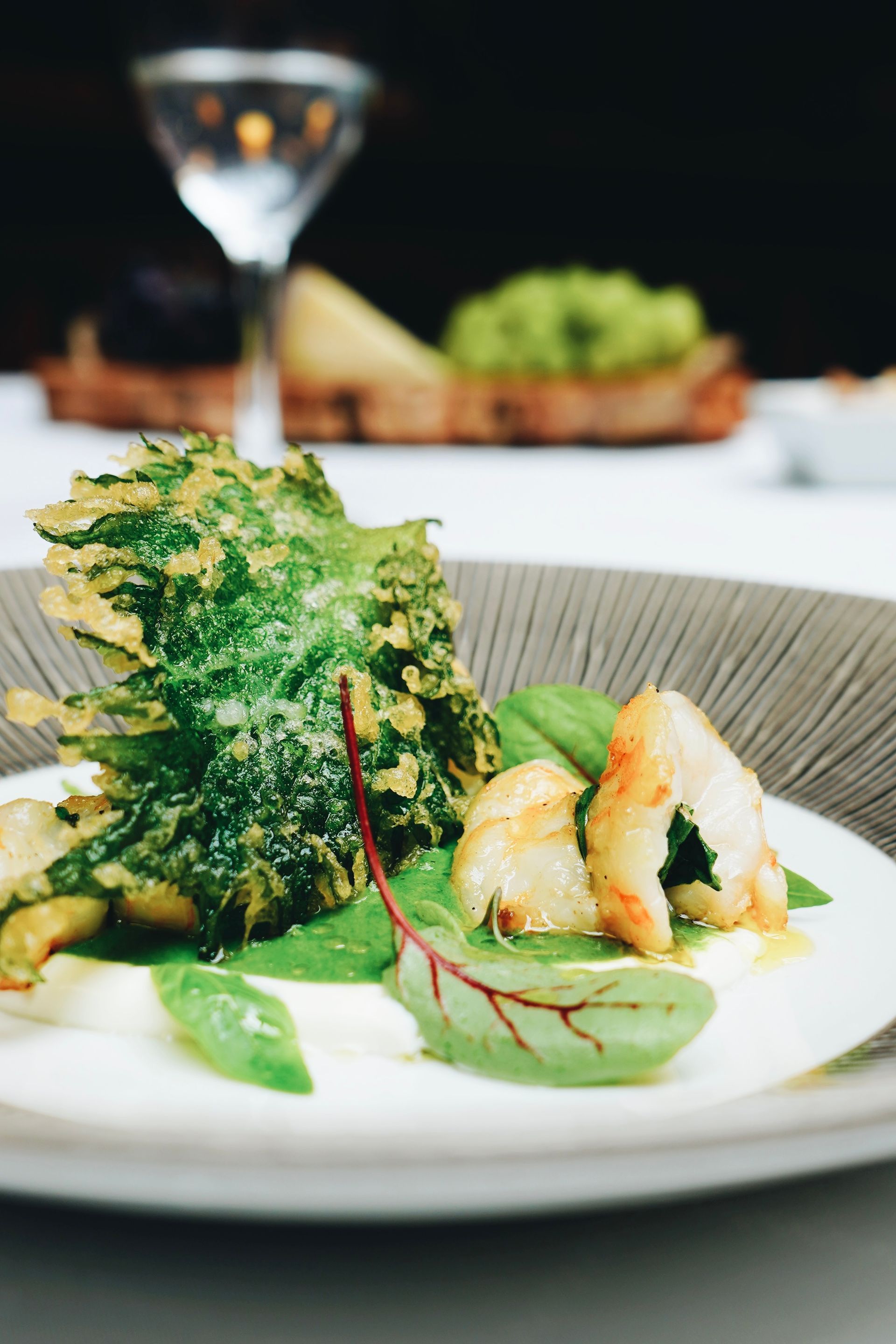 Un primer plano de un plato de comida con una copa de martini al fondo.