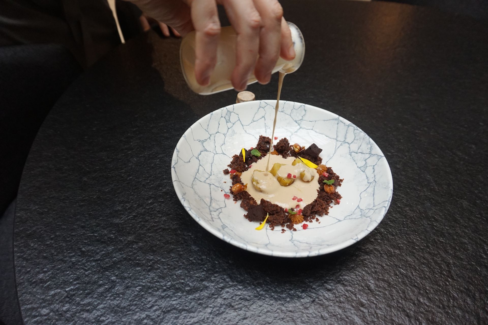 Una persona está echando salsa en un plato de comida.