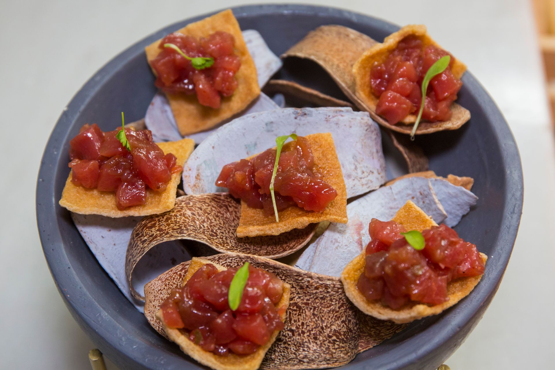 Un cuenco lleno de tortillas y salsa sobre una mesa.