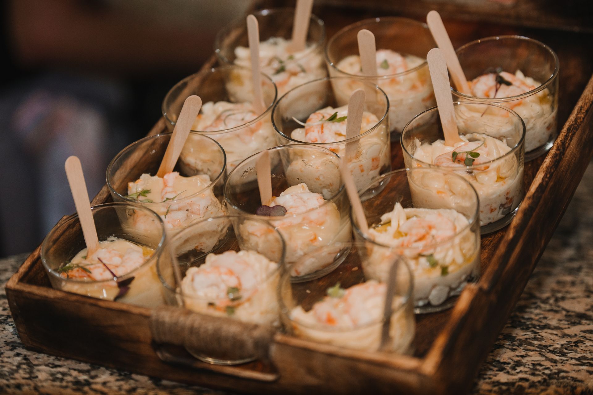 Una bandeja de madera llena de vasos llenos de comida y cucharas.