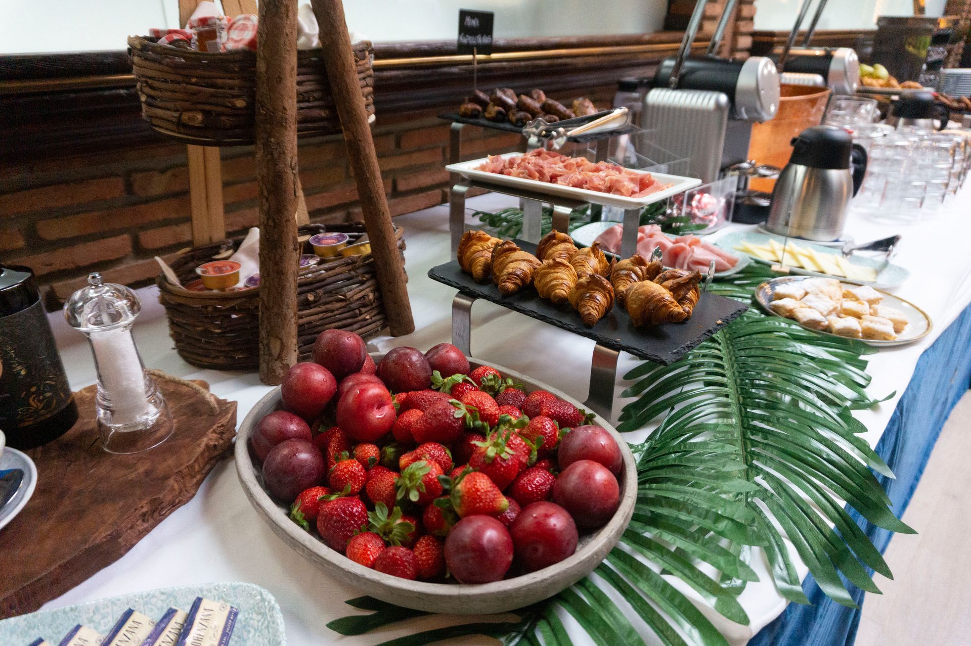 Una mesa de buffet con un plato de fresas y ciruelas encima.