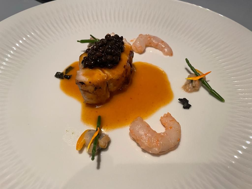 Un plato de comida con camarones y salsa.