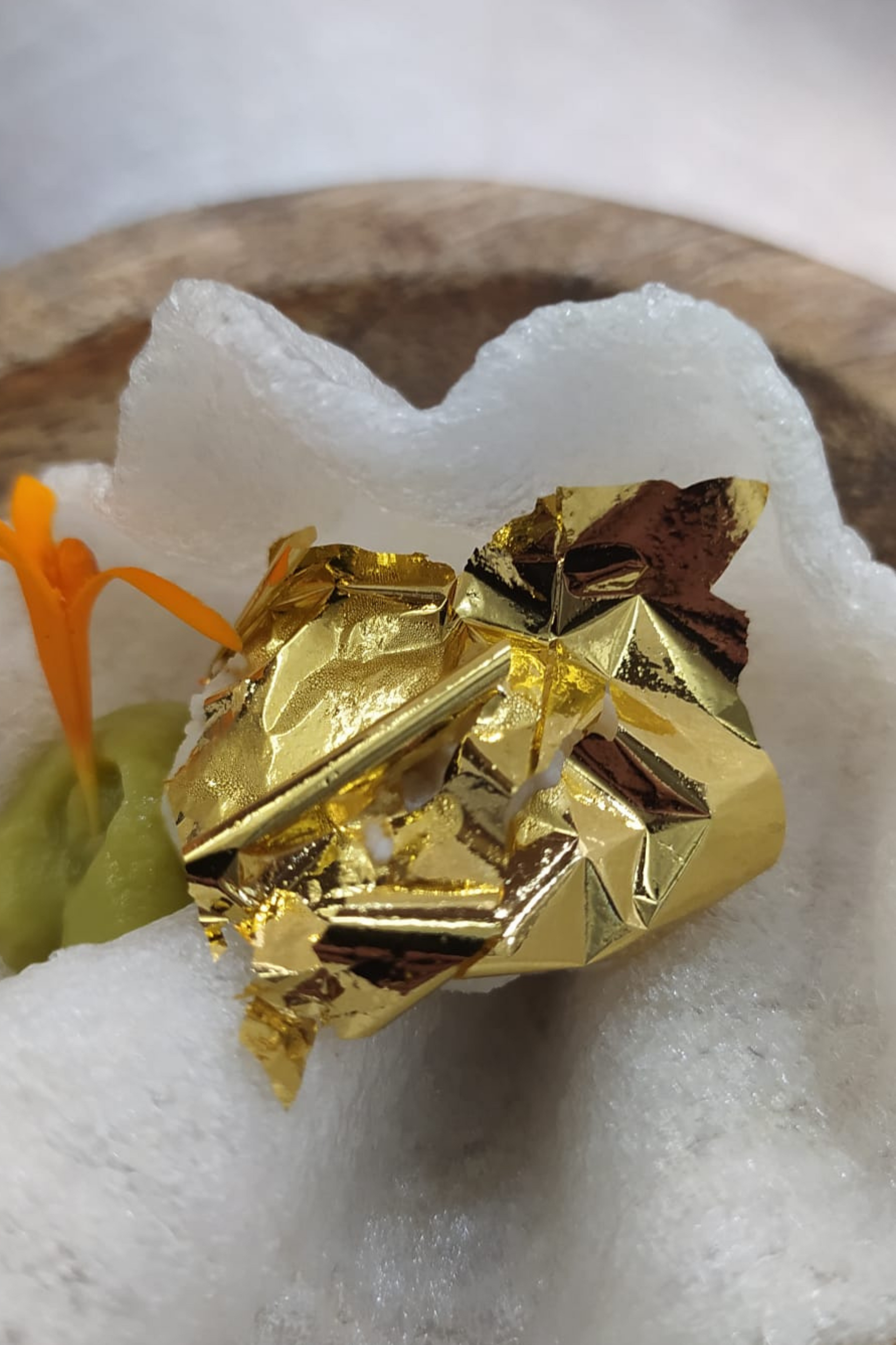 Un primer plano de un trozo de lámina dorada sobre un plato de comida.