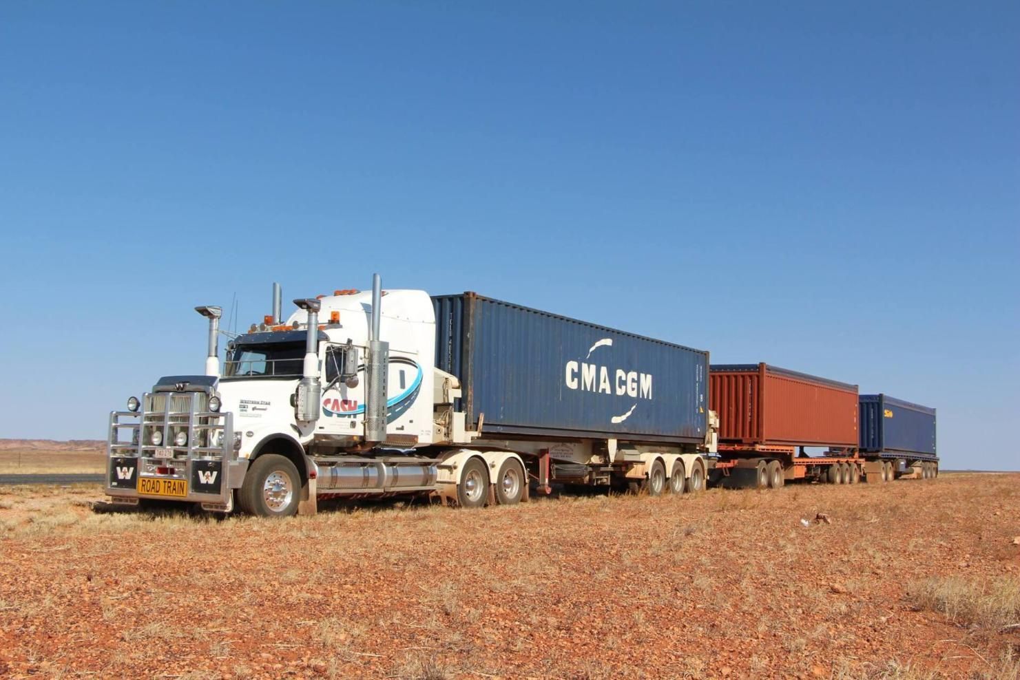 A Large Semi Truck Is Driving Through a Desert Carrying Shipping Containers — Spinifex Container Solutions In Ciccone, NT
