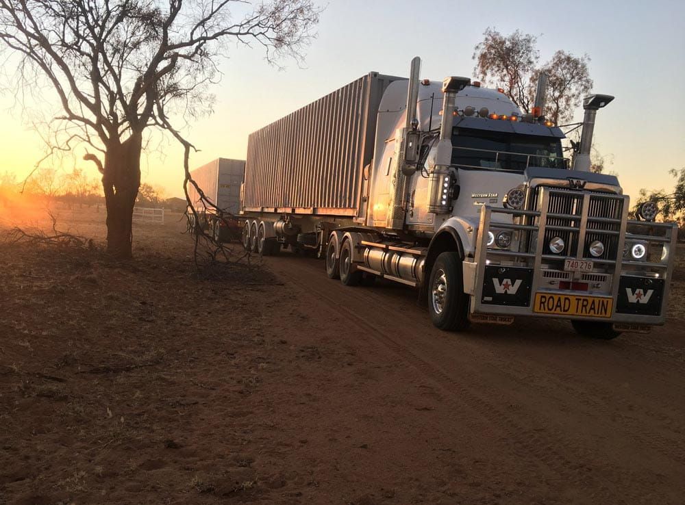 A Large Semi Truck Is Parked on A Dirt Road at Sunset — Spinifex Container Solutions In Ciccone, NT