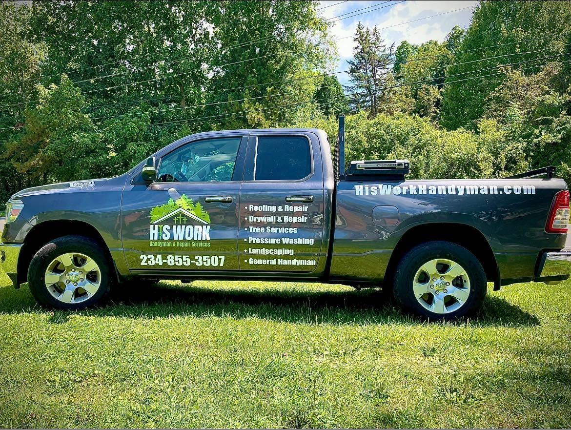 A gray truck is parked in the grass with trees in the background.