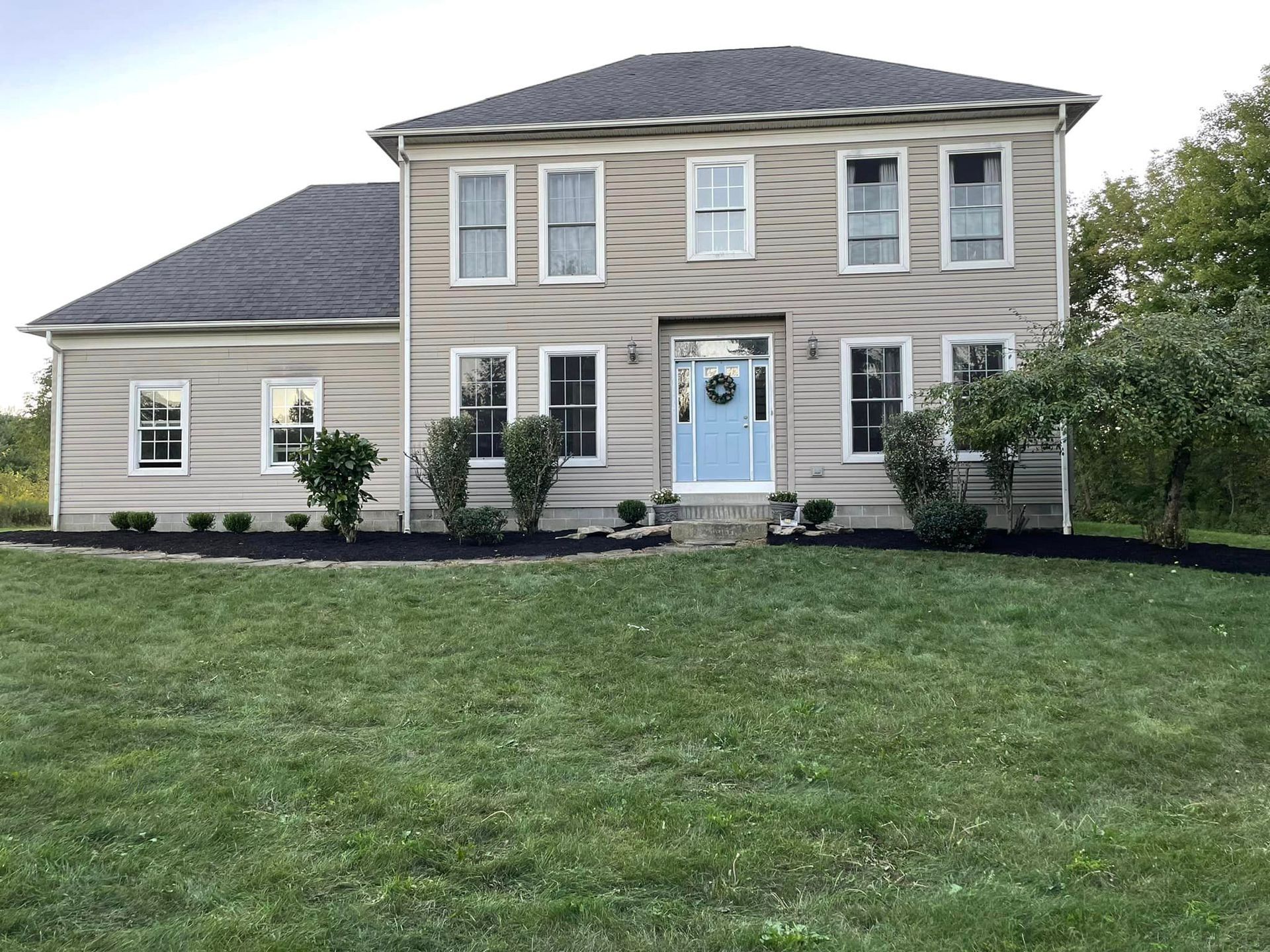 A large house with a blue door and a large lawn in front of it.