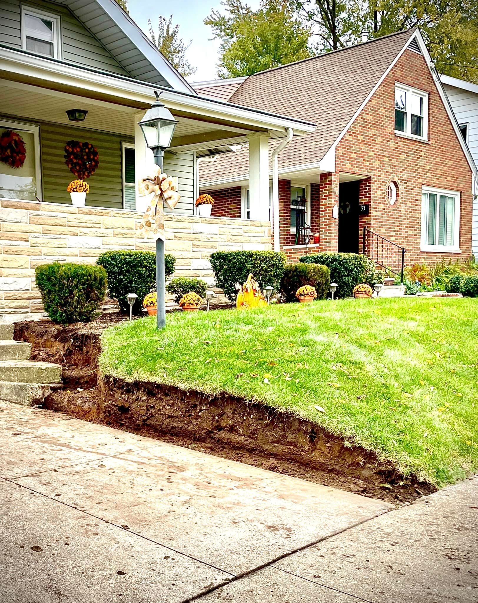A brick house with a lush green lawn and stairs in front of it.