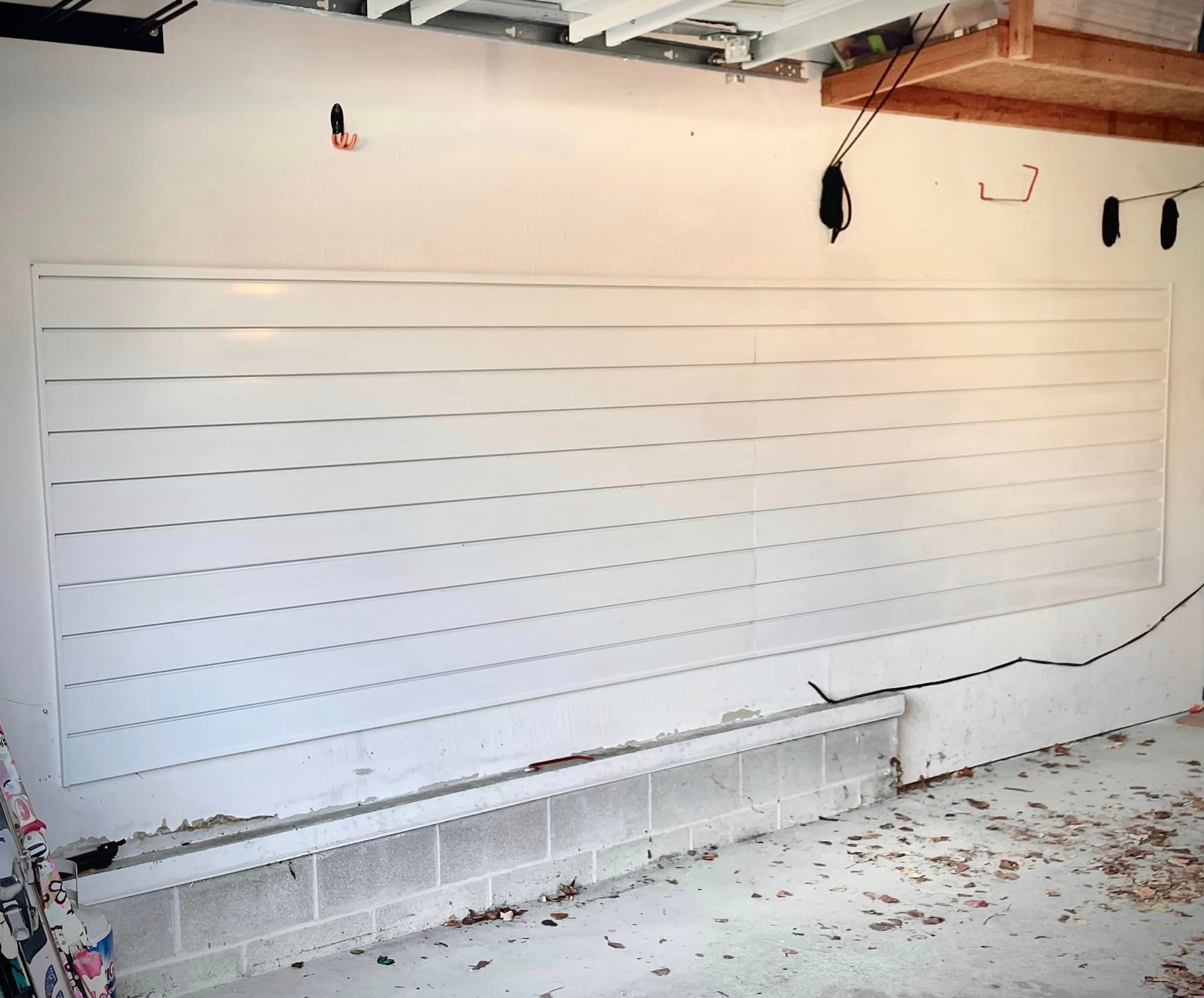 A white wall in a garage with hooks on it