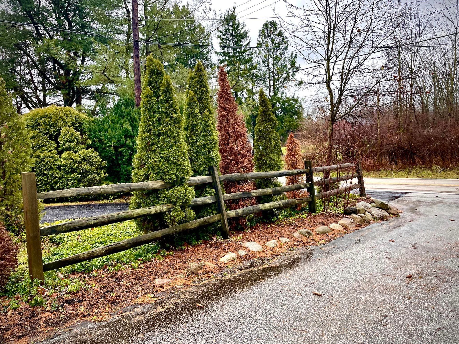 A wooden fence surrounds a road with trees in the background.