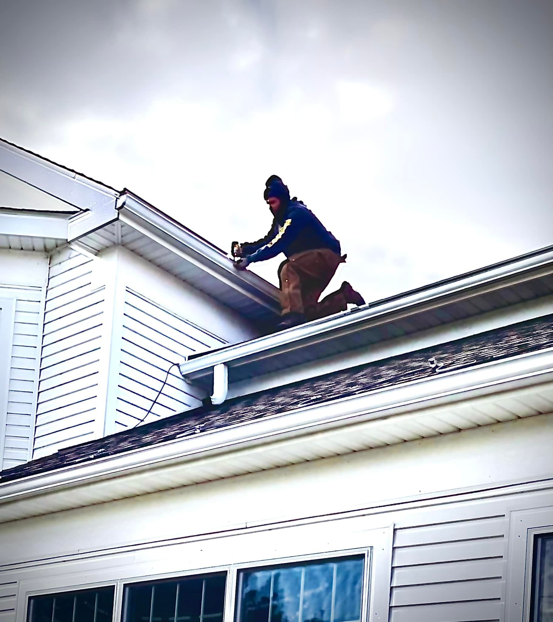 A man is kneeling on the roof of a house