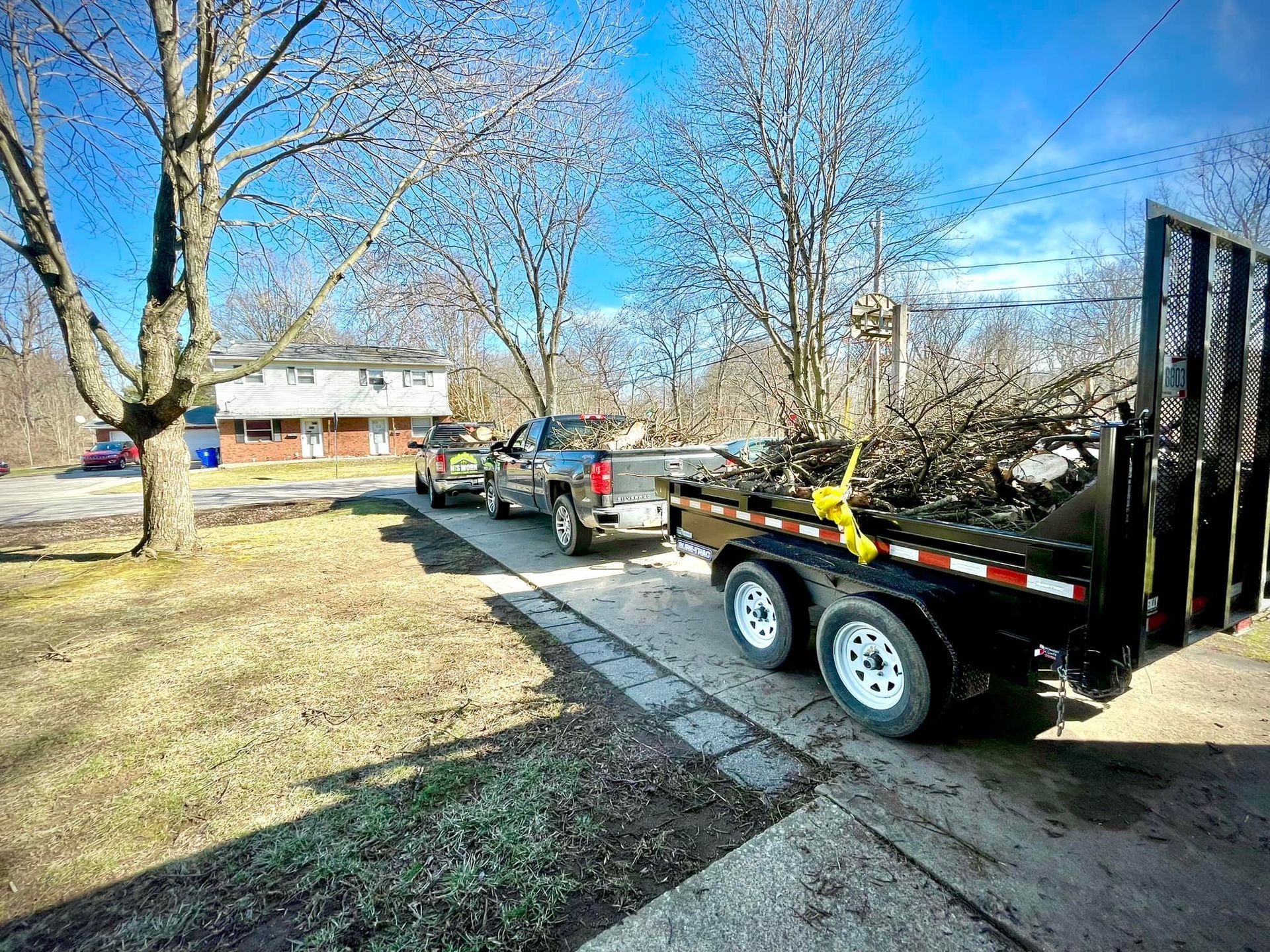 A dump trailer is parked on the side of the road next to a truck.