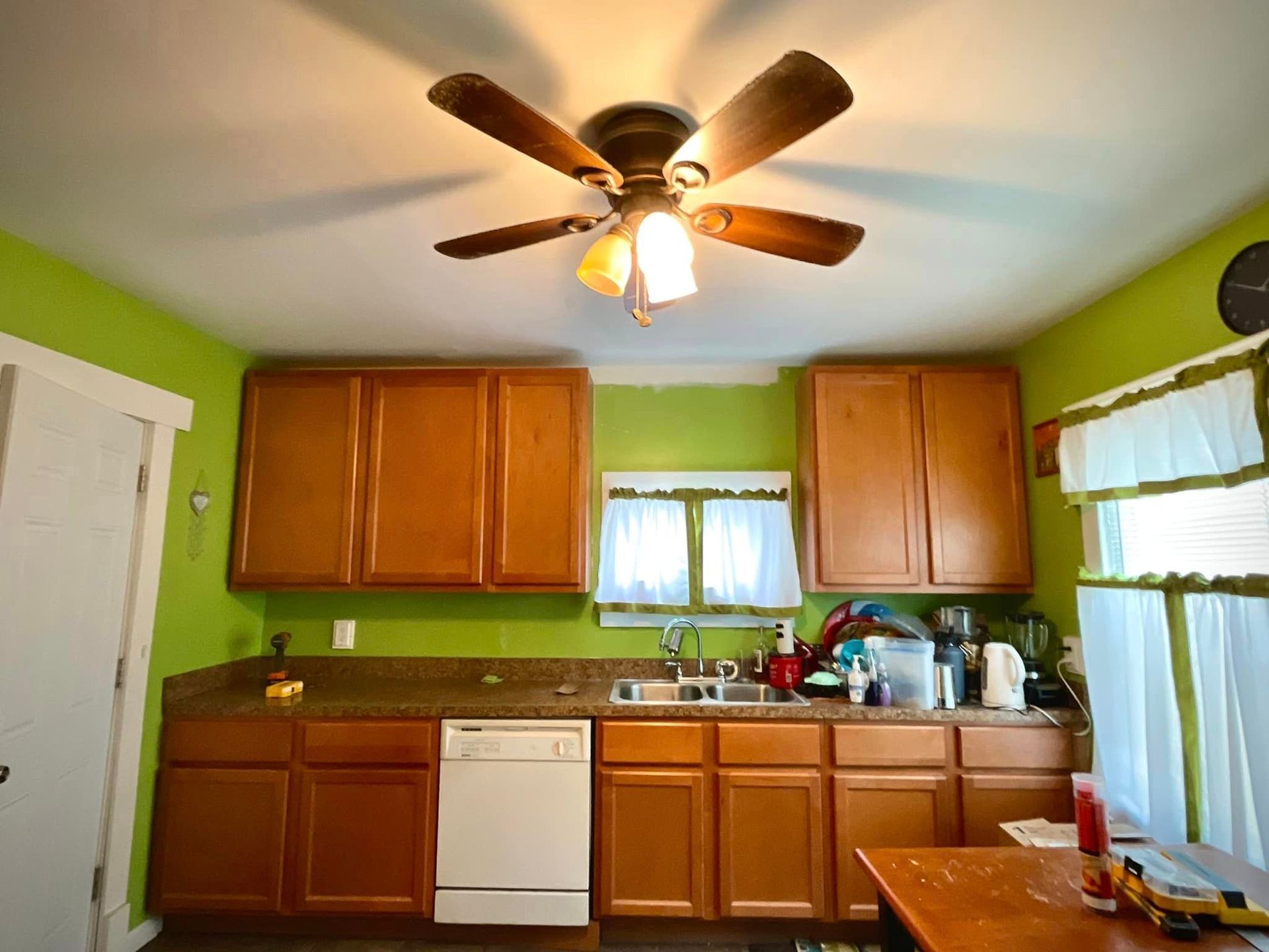A kitchen with wooden cabinets and a ceiling fan