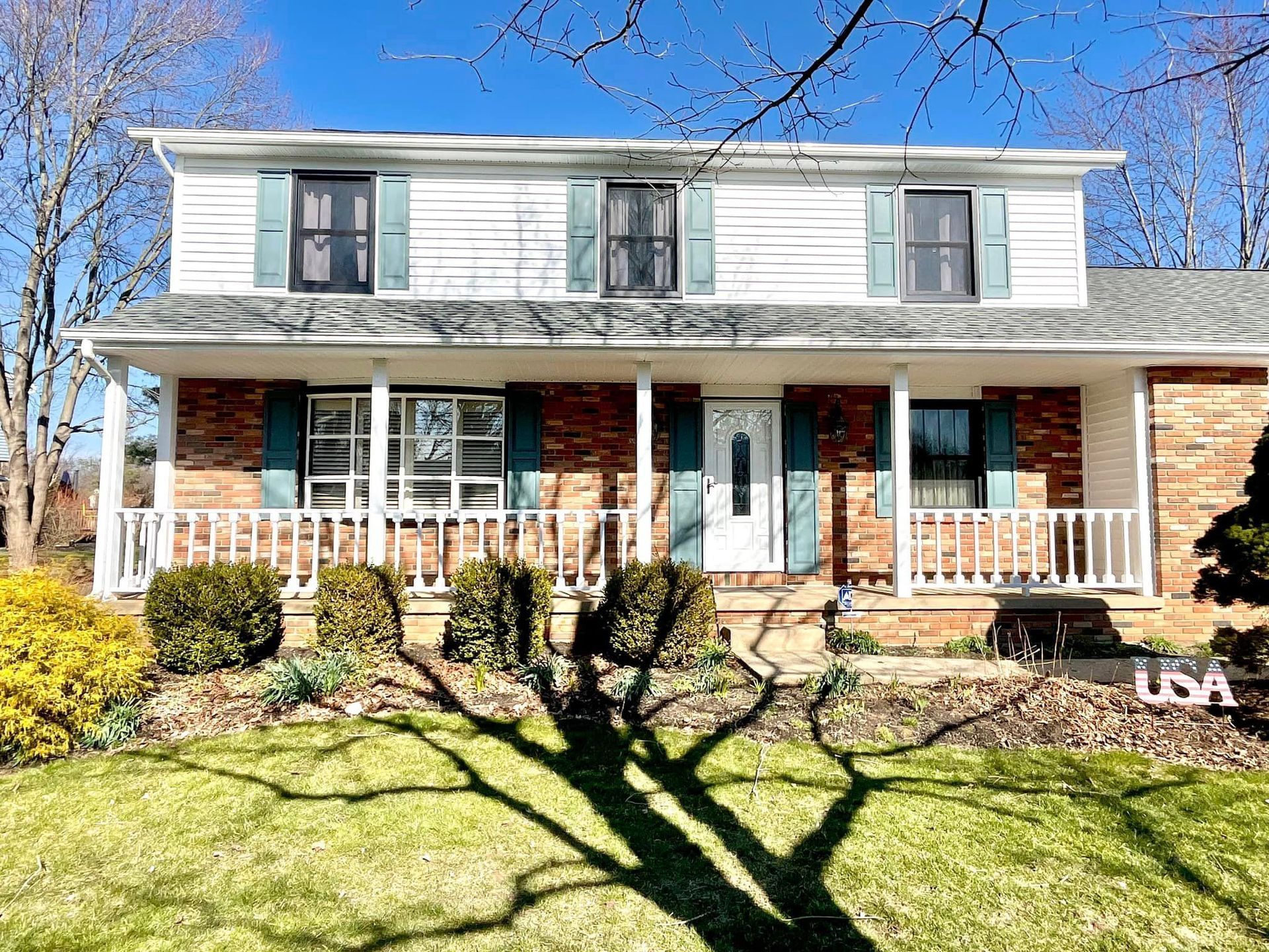 A large white house with blue shutters and a large porch.