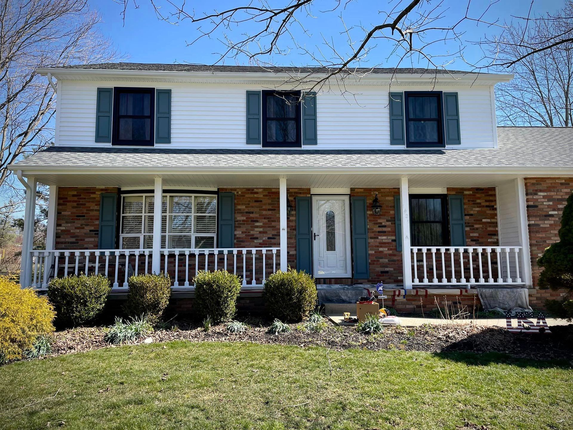 A large white house with a large porch and black shutters.