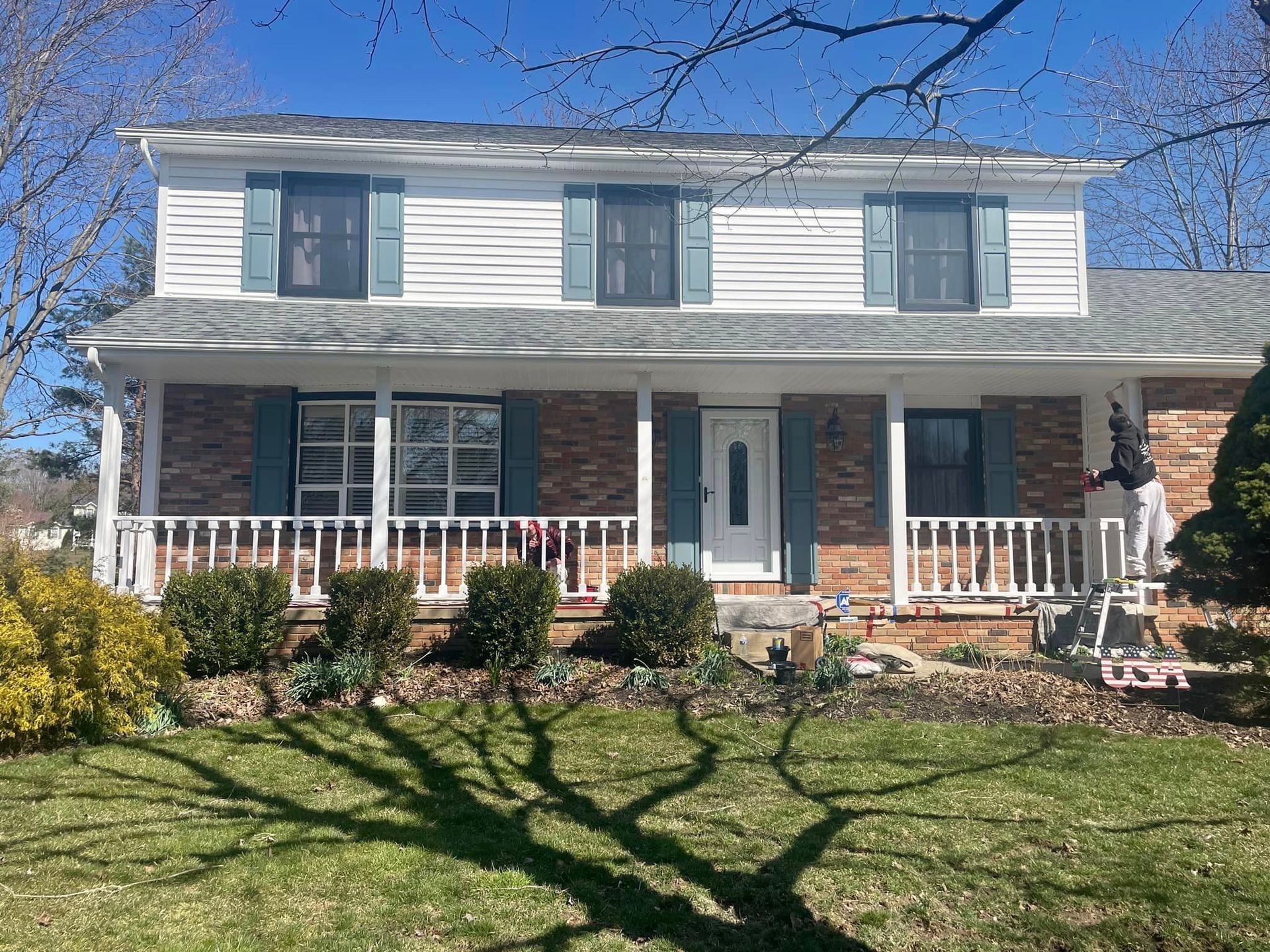 A large brick house with a large porch and shutters.