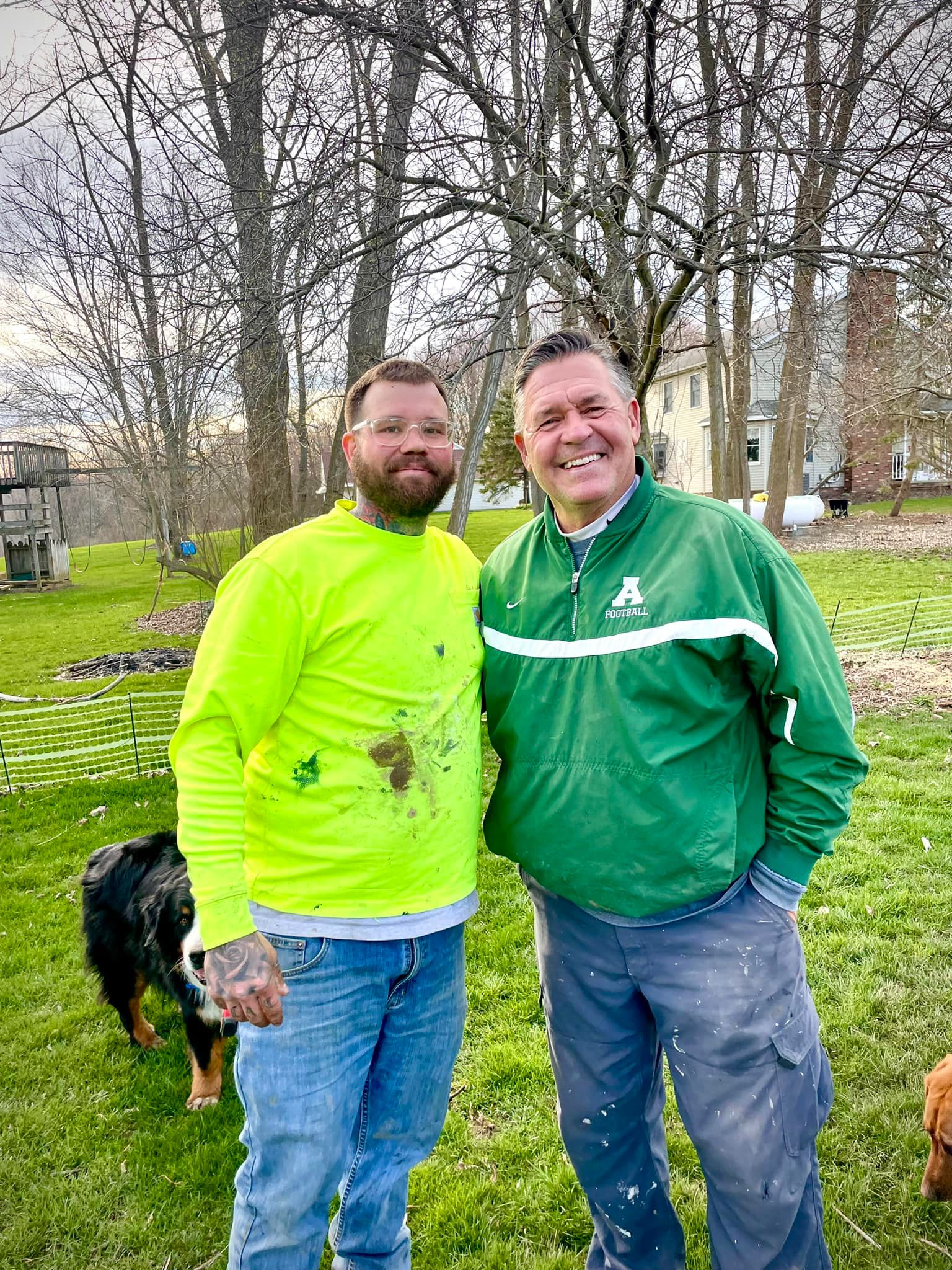 Two men are standing next to each other in a grassy field.